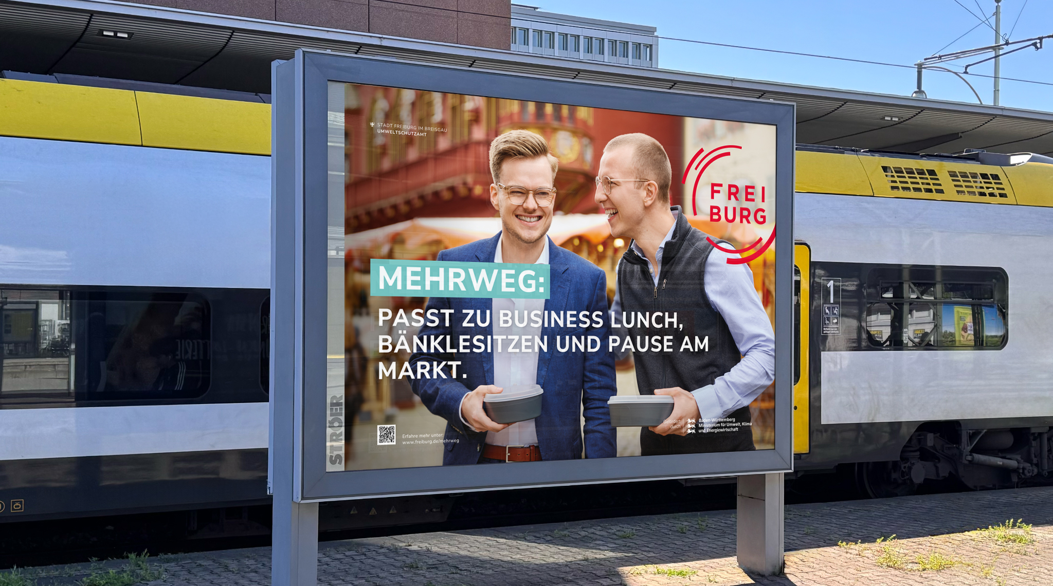 Mehrweg-Plakat am Bahnhof: zwei Männer mit Mehrwegschalen, „Passt zu Business Lunch, Bänklesitzen und Pause am Markt.“