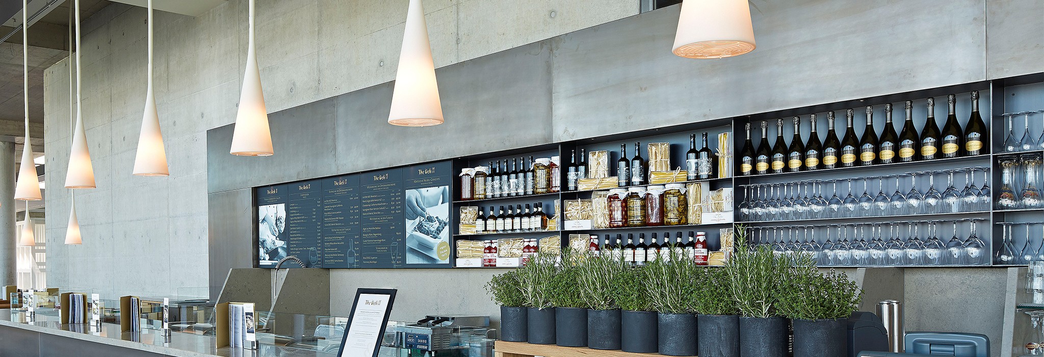 The Deli: Bar mit Pendelleuchten, Flaschenregal und Kräutertöpfen